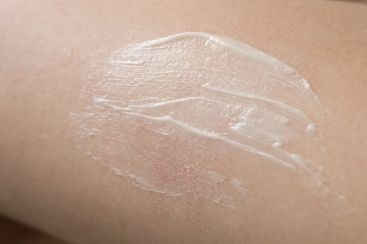 Application d’un baume émollient sur l’avant-bras d’une peau sèche atopique
